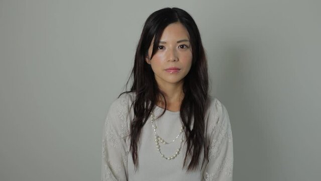 Beautiful Japanese woman opens her eyes and stares the camera. Emotionless, Still, Protest. Dolly out.