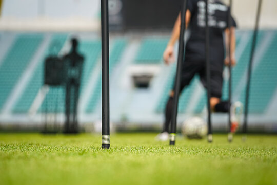 Obstacle post equipment for football dribbling with a player do the training as blur background. Professional football training scene photo, close-up and selective focus on the front post.