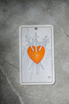 November 18, 2022 - Kyiv, Ukraine. Ryder's Tarot - Waite. The Junior Arcana of the suit of swords. III, 3.  Esoteric tarot cards for divination on a gray marble background