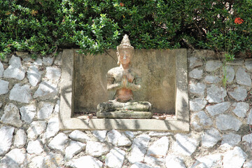 Deva statue with greet act on concrete wall