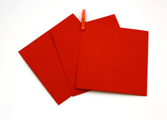 Red colored note papers shot on White background while purple clothespin hold them.