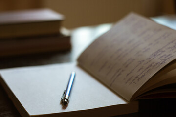 Open Notepad with handwritten notes with blue pen, books in the background - 547434586