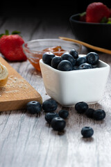 Containers with blueberries and strawberries and a container with passion fruit jam.
