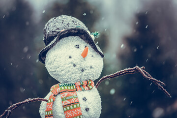 Portrait of a cute plush snowman in during the first snow of the year in a garden outdoors