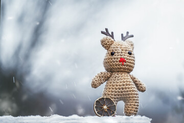 Portrait of a cute crocheted reindeer during the first snow of the year in a garden outdoors