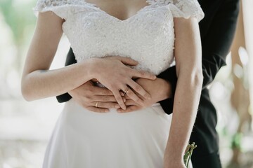 A Hispanic lesbian couple holding hands with rings with wedding dress