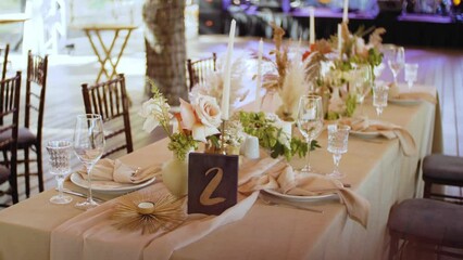 Beautiful wedding table decor, all decorated in pastel colors, camera moving . Festive served plates, glasses on the table, sun light rays on the table.