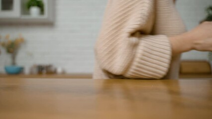 A woman takes a white ceramic cup from the table in the kitchen. A cup for tea and coffee. Modern kitchen design. A housewife with an elegant manicure. Dishes for liquids and hot drinks