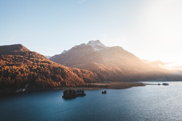 Lake surrounded by hills and mountains covered with vegetation under the sunlight
