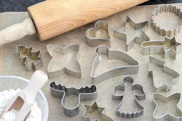 different cookie cutters for Christmas on baking paper and a rolling pin