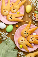 Easter bunny buns from yeast dough on a pink plates. Traditional Easter dessert rabbits, symbol, concept, decoration. Top view 