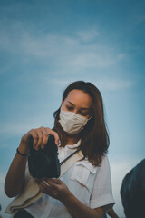 Young woman checking her camera with beautiful sky in background
