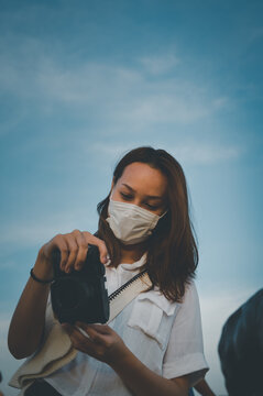 Young woman checking her camera with beautiful sky in background