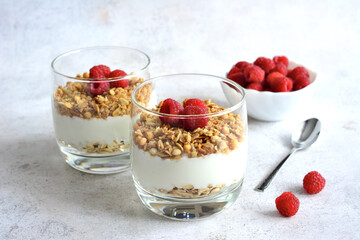 healthy dessert with oat flakes, yoghurt and raspberry in drinking glass isolated 