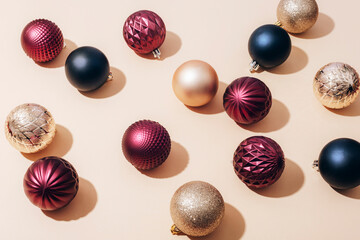 Colorful Christmas balls on light beige background with sharp shadows. Top view, flat lay, copy space