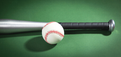Baseball bat and baseball on the green background.