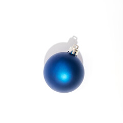 Blue Christmas ball on white background with sharp shadow. Top view