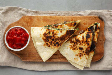 Homemade Spinach and Mushroom Quesadilla with Salsa on a rustic wooden board, top view. Flat lay, overhead, from above.