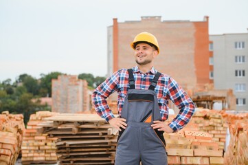 Yellow colored hard hat. Young man working in uniform at construction at daytime.