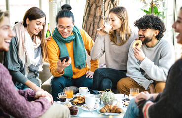 Trendy friends watching menu on mobile phone at coffee bar - Young people having fun together at...