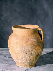 Vintage shabby clay jug with handle on a concrete surface