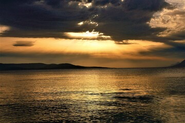 Sunset in the sea with dramatic clouds and rays of light