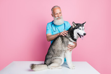 Full length photo of good mood positive careful man dressed blue uniform stethoscope on neck pet husky isolated on pink color background