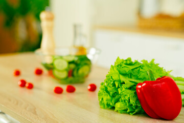 Bulgarian red pepper, green lettuce on table in kitchen. Fresh vegetables. Close up. Food concept. Health food.