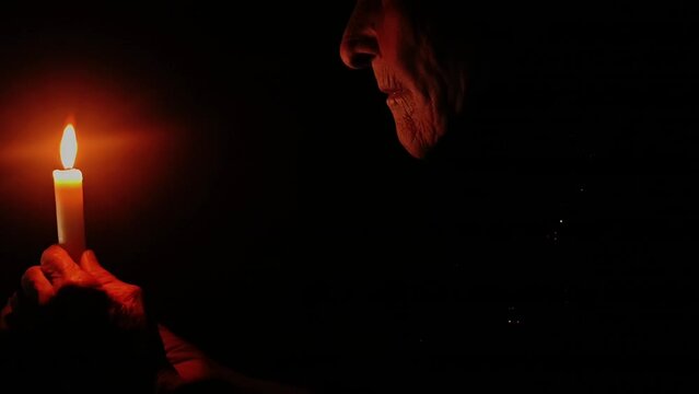 An old grandmother in a de-energized apartment. War in Ukraine. Destruction of Ukrainian power plants. Ukraine without light. Stop war. Russian aggression against Ukraine. Peace concept