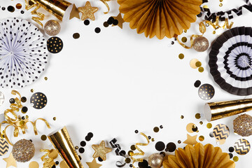 New Years Eve frame of gold and black confetti, noisemakers, streamers and decorations. Above view on a white background.