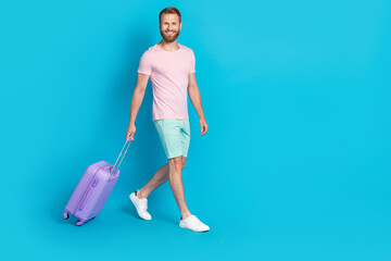 Full length photo of nice young guy baggage walking departure airport dressed stylish pink clothes isolated on aquamarine color background