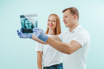 Doctor dentist and woman patient watching x-ray foto with teeth in in light blue background in dental clinic. Smile healthy teeth concept