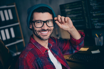 Photo of smart cheerful guy dressed eyewear smiling hacking websites modern device indoors...