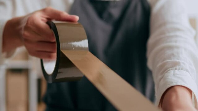 Packing cardboard boxes with adhesive tape for gluing cardboard boxes of goods, stock worker packs a parcel of goods to be sent to a transport company on the route to the courier
