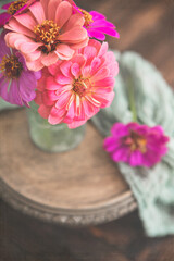 Close-up of Small Bouquet of Zinnias in an Antique Green Bottle on Wooden Table