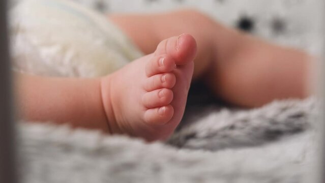 Baby twitches legs while lying on bed. Newborn baby feet together, infant foot first week of life. Sweet Newborn Baby Feet. Tiny Human Feet of Neonate Toddler is in Focus. Concept of Childhood 4k 