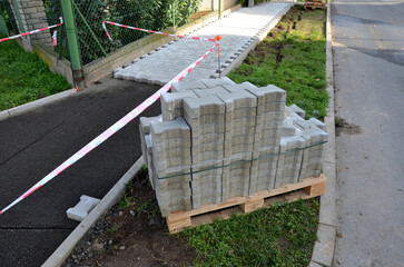 laying concrete paving in a lane between curbs. the edges of the tile cubes must be shortened and fit into the gaps. reciprocating saw. laying gravel, paving, cycle path, landscaping and earthworks