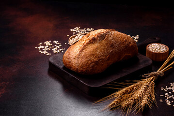 A loaf of brown bread with grains of cereals on a wooden cutting board