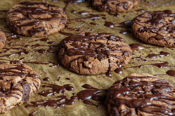 Topping with chocolate threads over cookies on a baking sheet.