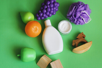 Organic care shampoo, moisturizing facial cream, sponge and toys on a green background. Natural skin and hair care cosmetic products
