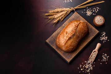 A loaf of brown bread with grains of cereals on a wooden cutting board