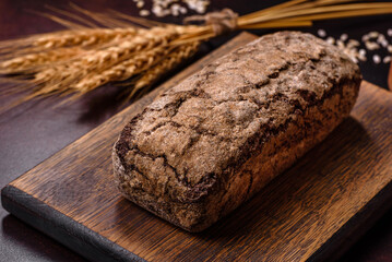 A loaf of brown bread with grains of cereals on a wooden cutting board