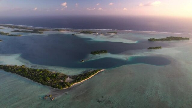 Aerial panning shot of tropical atoll at sunset