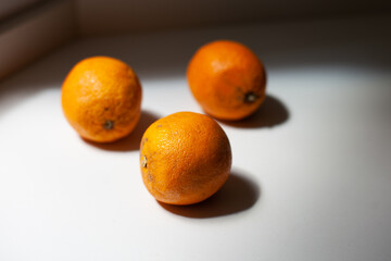 Imperfect sustainable oranges. Organic fruit on the kitchen table. Orange season in Spain. Three ripe oranges in the sunlight. misshapen, scarred or slightly bruised fruits.are thrown away by farmers 