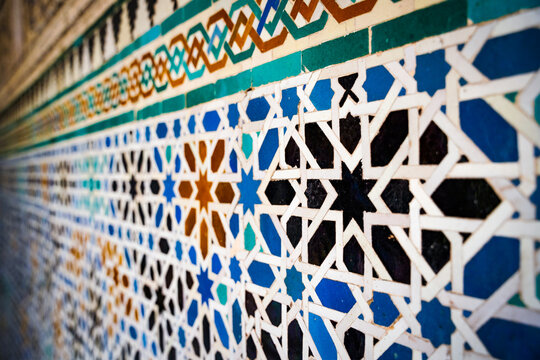 Geometric seamless andalusian moroccan islamic arabic star pattern in blue made out of ceramic tiles in Spain Sevilla off-focus foreground