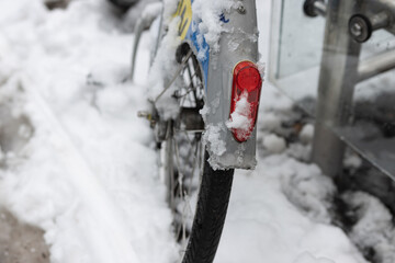 The rear light of the bike is covered with snow. Cycling in winter