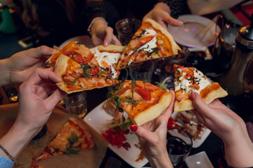Friends taking slices of tasty pizza from plate, close up view.