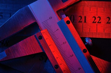 caliper and metal rulers illuminated in red and blue. close-up