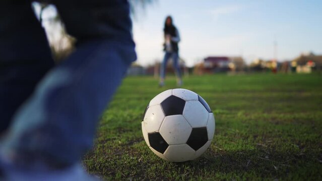 Boy kicking a football on a green meadow. Child dream of football match. Sports training in park. Child playing soccer outdoor.