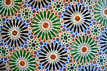 Fototapeta na wymiar Geometric seamless andalusian moroccan islamic arabic round star floral pattern in green orange made out of ceramic tiles in Spain Sevilla